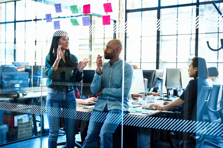 Attractive businesswoman in jeans and shirt, standing by male manager, discussing ideas in brainstorming session, planning, explaining